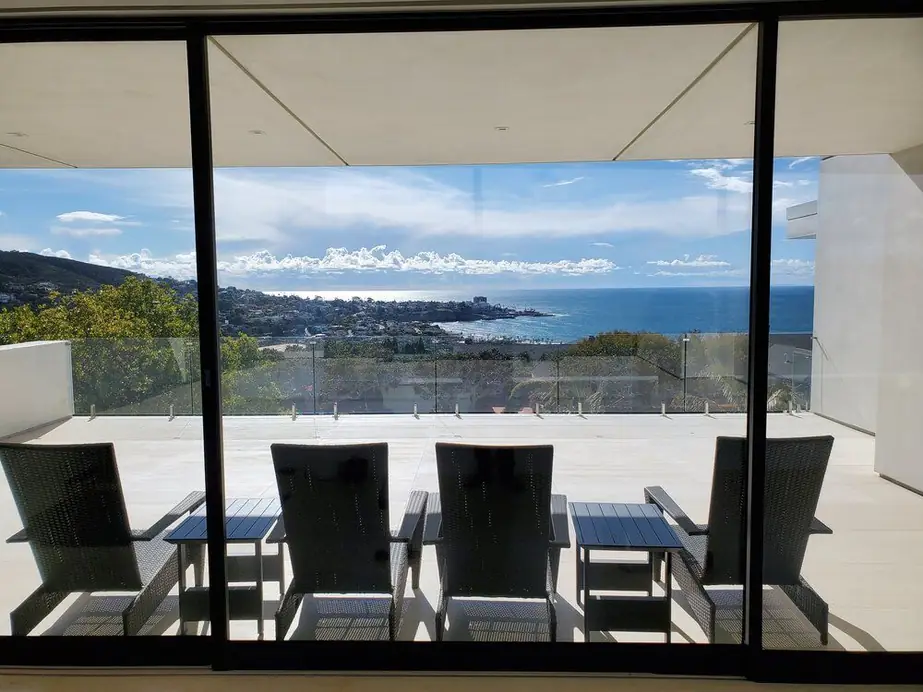A corner window nook framed in slim aluminum, looking out over a Southern California coastal hillside