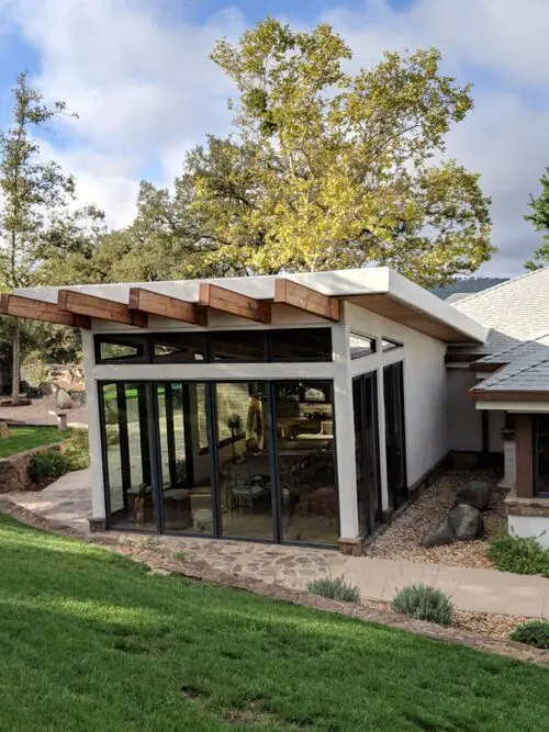 A modern glass-walled addition set against a California hillside