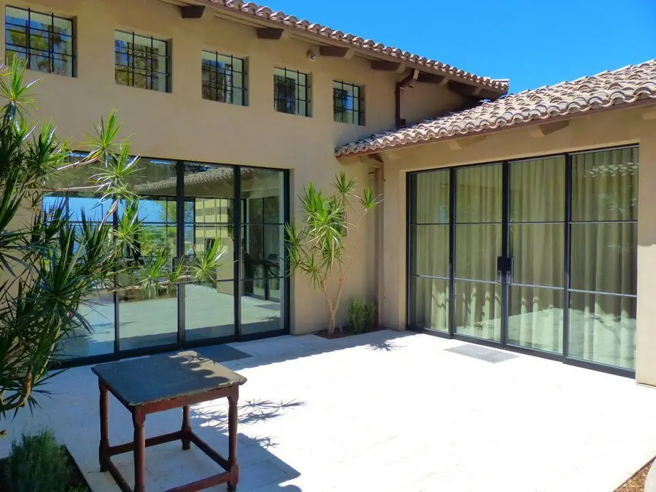 Black steel-framed windows and doors on a Southern California home with a tiled roof and courtyard