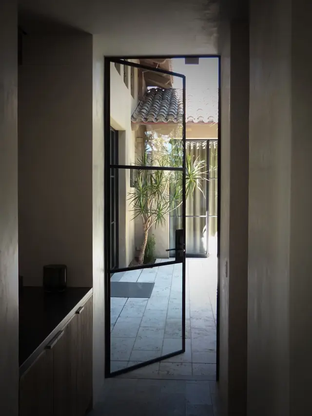 A black steel-framed door and window installation on a Southern California home