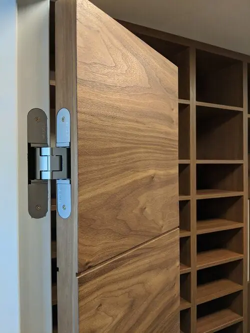 A walnut door on concealed hinges, hung against fitted shelving